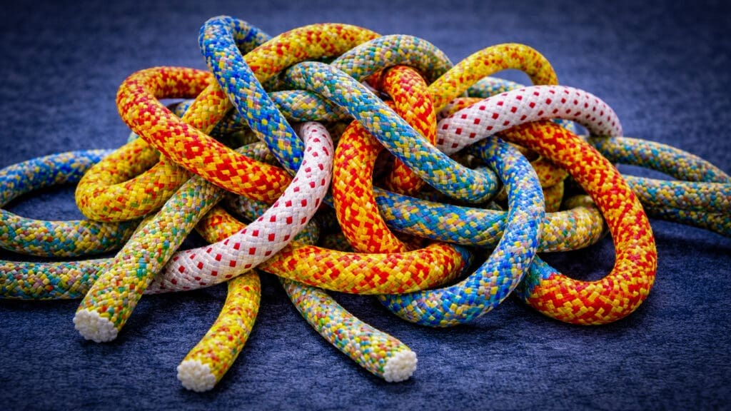 Verstrengelde kleurrijke touwen als metafoor voor een vastgelopen fusie of complexe samenwerking