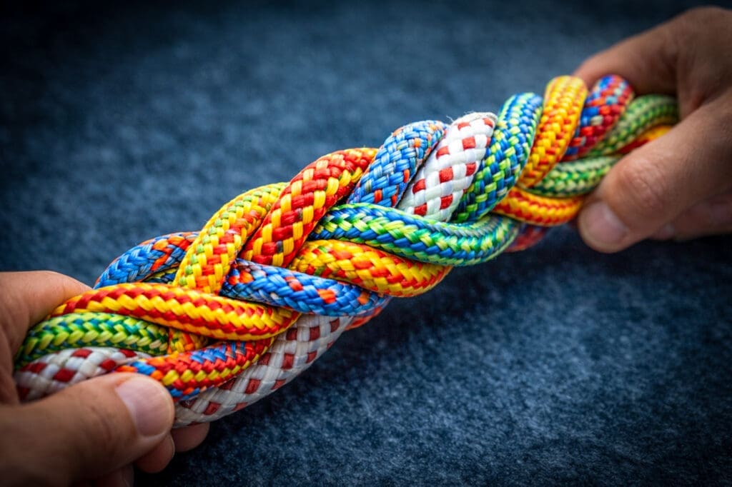 Handen houden een gevlochten bundel touwen vast als metafoor voor spanning en samenwerking