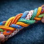 Handen houden een gevlochten bundel touwen vast als metafoor voor spanning en samenwerking